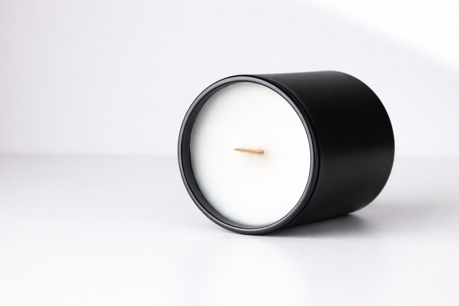 Black candle with a white center on a light gray background